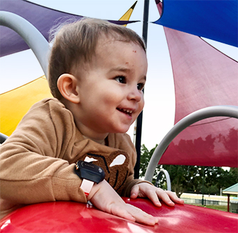 Toddler wearing activity watch, playing on playground equipment