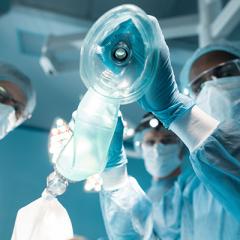 anaesthetist holding oxygen mask above patient in surgery room